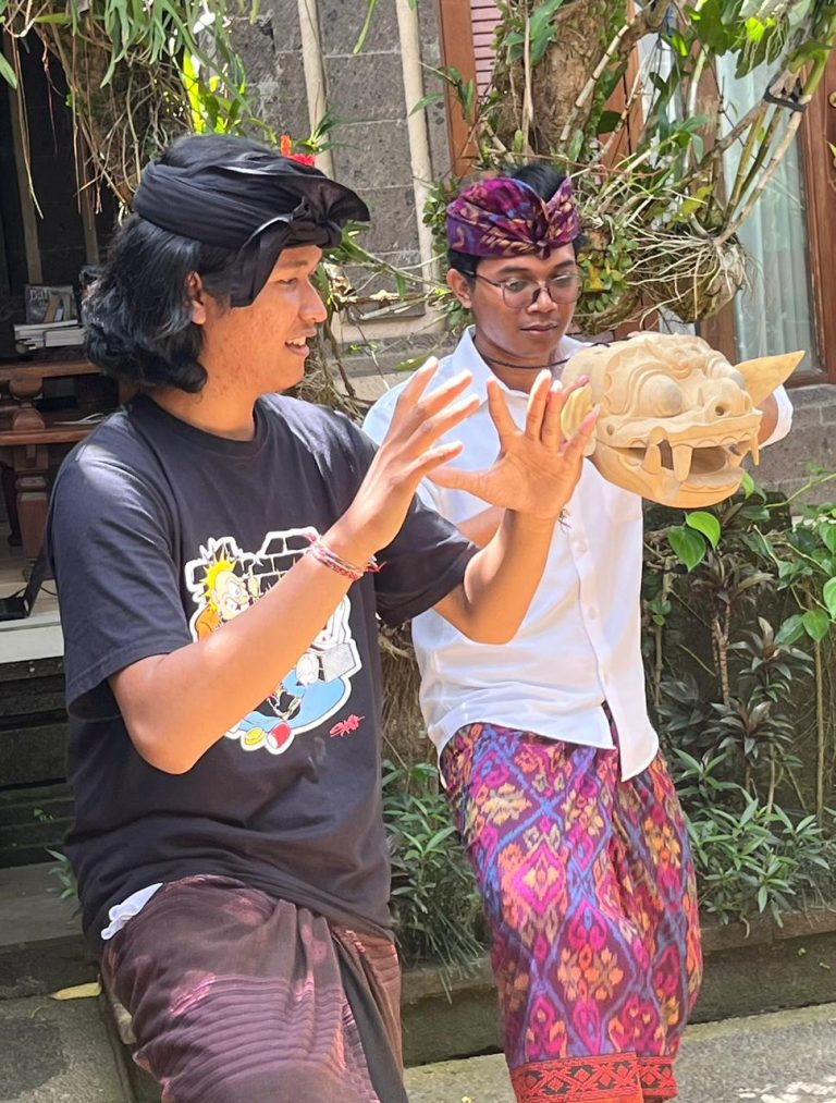 two balinese young men practicing a dance using a traditional balinese mask called Barong